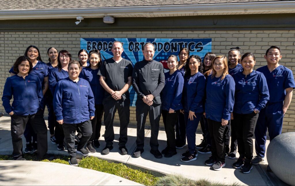 Brodsky Orthodontics team of board-certified orthodontists and staff in blue uniforms standing outside their office, showcasing a welcoming environment for orthodontic care in Lakewood.